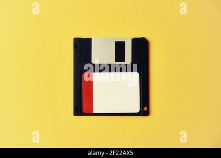 Black floppy diskette on yellow background. Vintage computer diskette, closeup Stock Photo