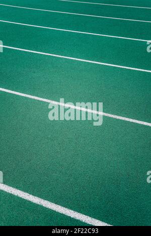 White lines marking lanes on a green athletics track running diagonally across the image Stock Photo
