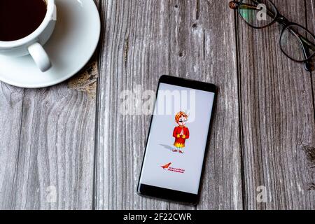 A mobile phone or cell phone laid on a wooden table with the Air India app open on screen next to a coffee Stock Photo