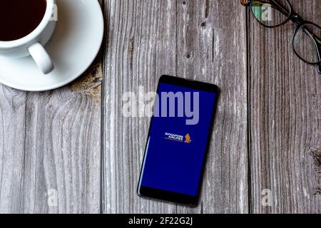 A mobile phone or cell phone laid on a wooden table with the Singapore airlines app open on screen Stock Photo