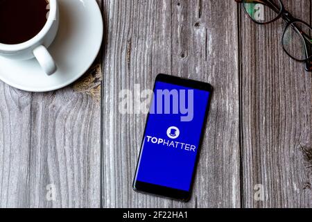A mobile phone or cell phone laid on a wooden table with the Tophatter auction app open on screen Stock Photo
