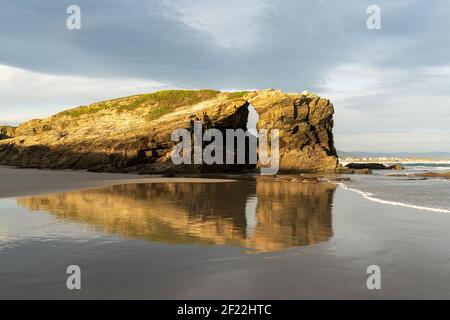 A beautiful beach with fine sand and rocky cliffs at sunrise Stock Photo