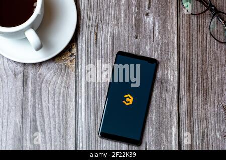 A mobile phone or cell phone laid on a wooden table with the Coinbase crypto currency app open on screen next to Stock Photo