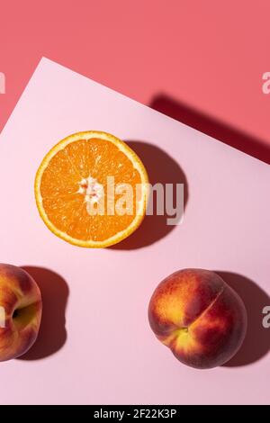 Orange fruit with peaches on bright background. Minimal food concept. Stock Photo