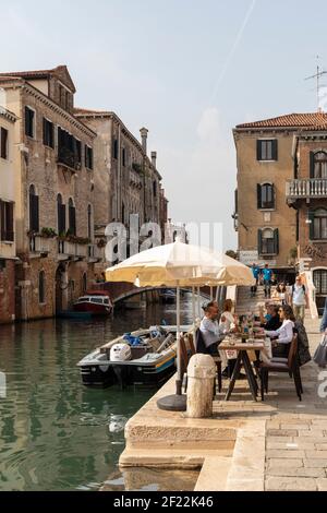 Tourists outside enjoying a meal at restaurants along Fondamenta dei Ormisini beside Rio della Misericordia, Cannaregio, Venice, Italy Stock Photo