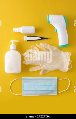 Medical gloves,disinfectant, thermometer, hand sanitizer and surgical mask on yellow background Stock Photo