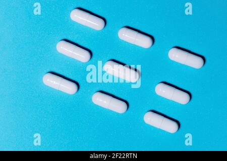 lots of white pills on the blue table . Stock Photo