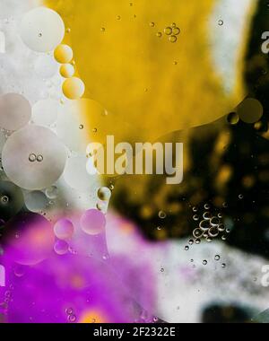 Bubbles on colourful background, oil bubbles on silver, yellow, pink, black background, soap and oil, oil bubbles in water with colourful backdrop Stock Photo