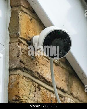 Home security camera in he snow, mounted on the wall below roof eave Stock Photo