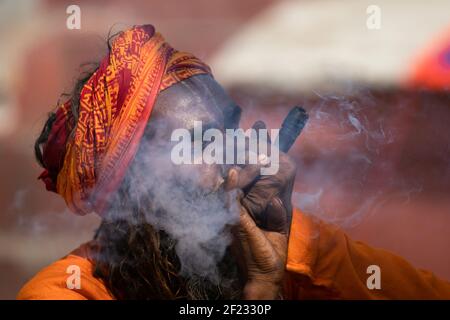 Kathmandu, Nepal. 10th Mar, 2021. A Hindu holy man, or sadhu, smokes marijuana at the Pashupatinath Temple ahead of the Shivaratri festival in Kathmandu.Hindu Devotees from Nepal and India come to this temple to take part in the Shivaratri festival which is one of the biggest Hindu festivals dedicated to Lord Shiva and celebrated by devotees all over the world. Credit: SOPA Images Limited/Alamy Live News Stock Photo