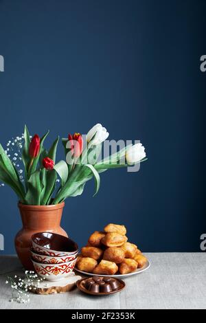 Kazakh national bowls kese, fried bread baursaks and tulips during Nauryz festival on blue background Stock Photo