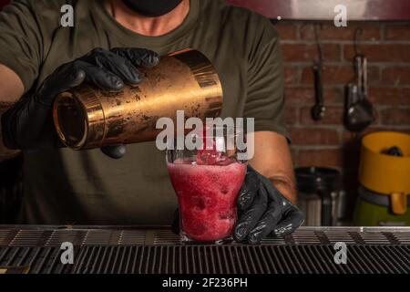 Barman in the bar pouring red alcohol cocktail in a glass. Summer party background. Stock Photo