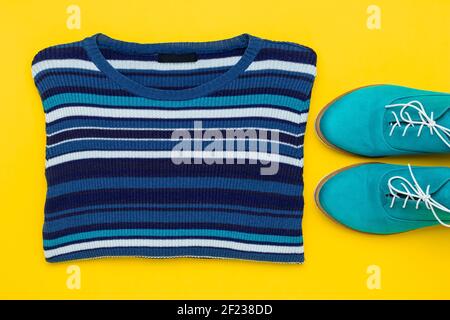 Pair of turquoise suede shoes. Demi-season aqua oxfords with white laces and knitted striped women's pullover on a yellow background, top view. Autumn Stock Photo