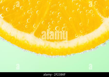 Close up view of a slice of orange in soda water with bubbles. Summer drink concept. Stock Photo
