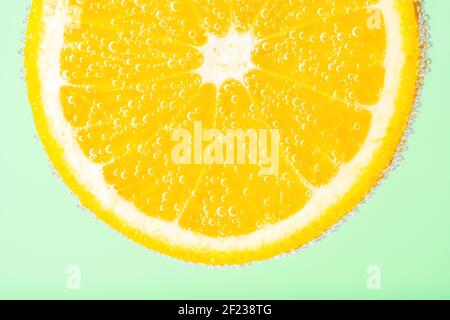 Close up view of a slice of orange in soda water with bubbles. Summer drink concept. Stock Photo