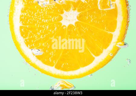 Close up view of a slice of orange in soda water with bubbles. Summer drink concept. Stock Photo