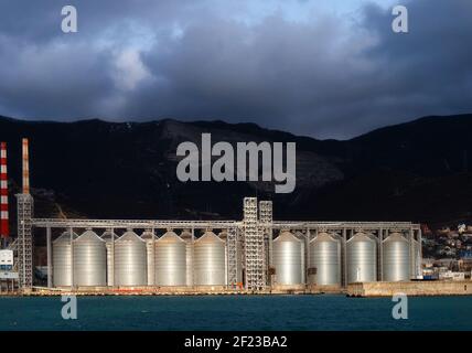 cisterns for storing grain in the port by the sea against the backdrop of the mountain Stock Photo