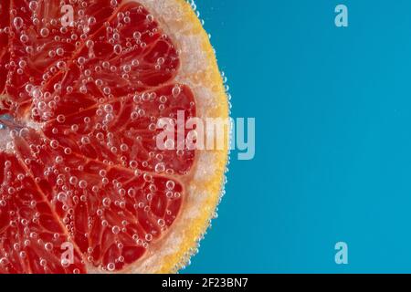 Close up view of a slice of grapefruit in soda water with bubbles. Summer drink concept. Stock Photo