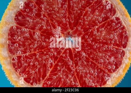Close up view of a slice of grapefruit in soda water with bubbles. Summer drink concept. Stock Photo