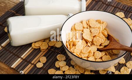 Healthy cornflakes and milk and a wooden spoon on a bamboo napkin. Stock Photo