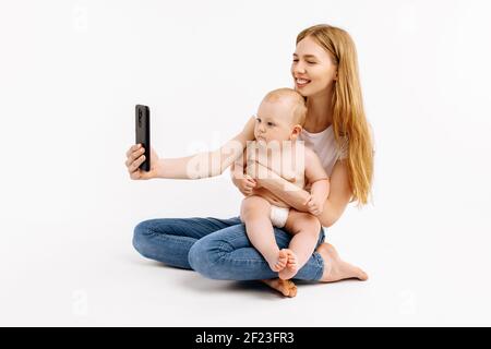 Happy mom and son making video call on smartphone, talking to dad or relatives, waving to mobile phone, remote communication, on an isolated white bac Stock Photo