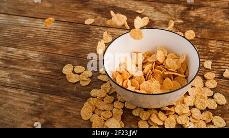 Cereals falling in a white bowl on a wooden table Stock Photo