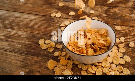 Cereals falling in a white bowl on a wooden table Stock Photo