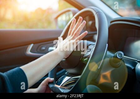 female hand presses the horn on the steering wheel of a modern car. no face Stock Photo