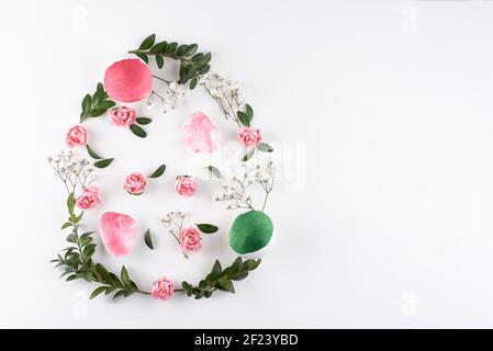 Easter egg made of flowers, green twigs, chives and eggs on a white background, copy space. Easter card. Stock Photo