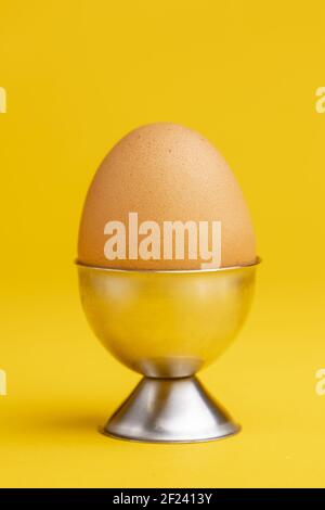 Egg in egg-cup on a seamless yellow background. Studio food still life against an even colorful backdrop. Stock Photo