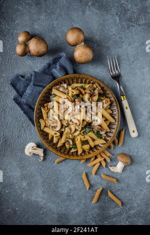 Flat lay photo of pasta penne with roasted mushrooms, garlic and zucchini. Italian food on blue marble table. Stock Photo