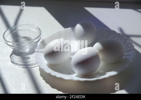 soft-boiled whole eggs in elegant white porcelain plate and empty sauce bowl Stock Photo