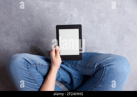 Subjective view of a young person holding an electronic reader with blank screen. Concepts: technology and reading. Image with copy space Stock Photo