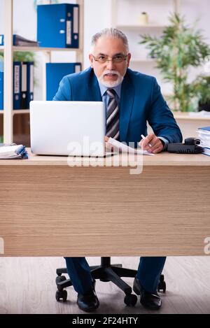 Old male bookkeeper unhappy with excessive work at workplace Stock Photo