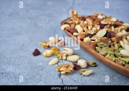 Mix dried fruits with nuts, pistachios, cashew nuts in wooden bowl on gray concrete background. Stock Photo
