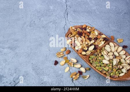 Mix dried fruits with nuts, pistachios, cashew nuts in wooden bowl on gray concrete background. Stock Photo