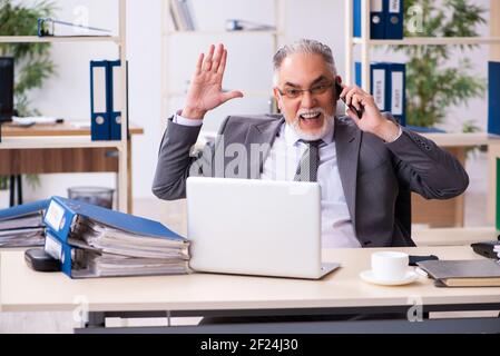 Old male employee using phone in the office Stock Photo