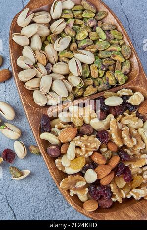 Mix dried fruits with nuts, pistachios, cashew nuts in wooden bowl on gray concrete background. Stock Photo