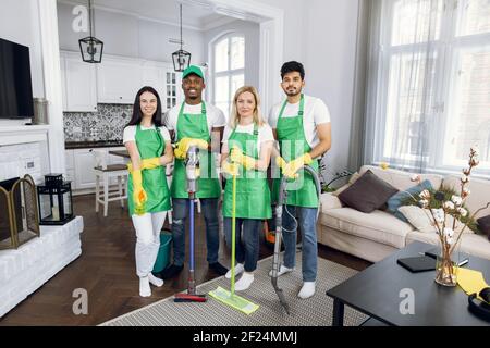 Four multiracial cleaners standing at modern apartment Stock Photo