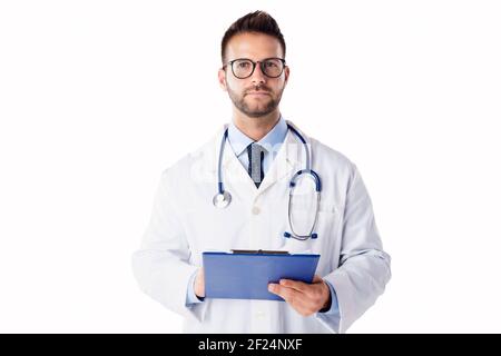 Studio portrait shot of young male doctor holding clipboard in his hand while standing at isolated white background. Stock Photo