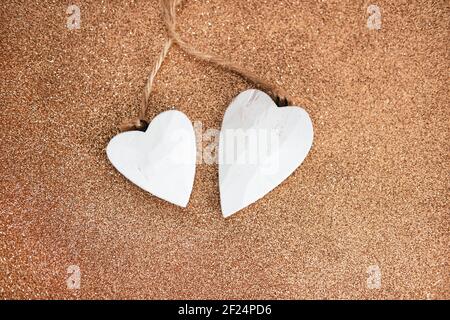Decorative white wooden hearts on brown glitter background. Two Valentine hearts. Saint Valentines Day or Love concept. Stock Photo