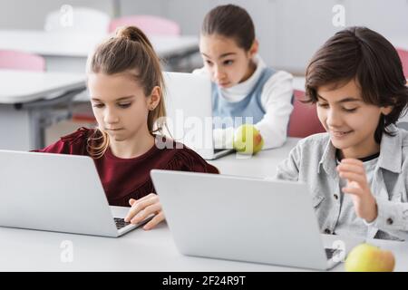 concentrated kids using laptop during lesson in school on blurred background Stock Photo