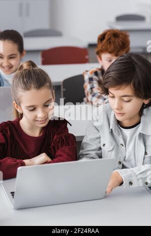 schoolchildren using laptops together during lesson in school Stock Photo