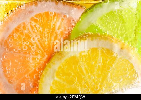 slices of lemon, orange and lime in fizzy mineral water Stock Photo