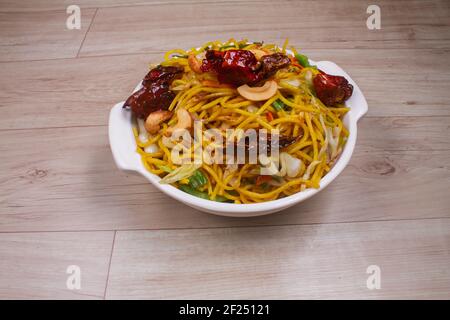 Egg noodles with barbeque pork on Chinese plates on a wooden table and garnish Stock Photo