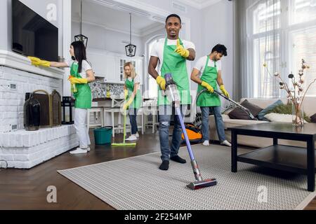 Four multicultural janitors doing cleaning at room Stock Photo