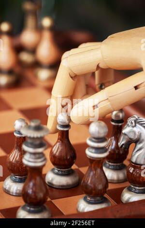 Cropped shot of robot hand playing chess, moving chess figure on chess board, selective focus. Concept of modern technology, strategy and tactic Stock Photo