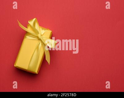 Rectangular box with a gift wrapped in yellow paper and tied with a silk yellow ribbon Stock Photo