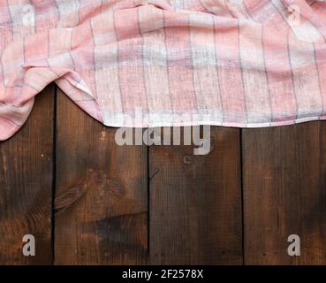 Folded pink white kitchen towel on brown wooden background, top view Stock Photo