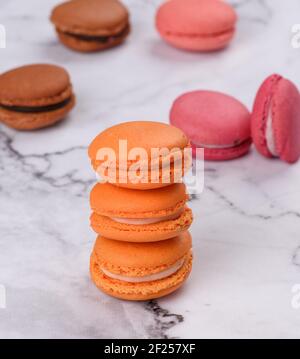 Stack of baked orange macarons on a white table Stock Photo